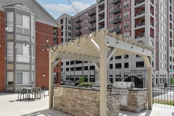 a patio with a grill and a pergola in front of a building at The Pointe at St. Joseph Apartments, South Bend, Indiana
